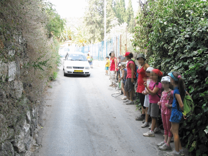 קבוצת ילדים נצמדת לדופן הרחוב העולה לבית ספר 'המעיין' 